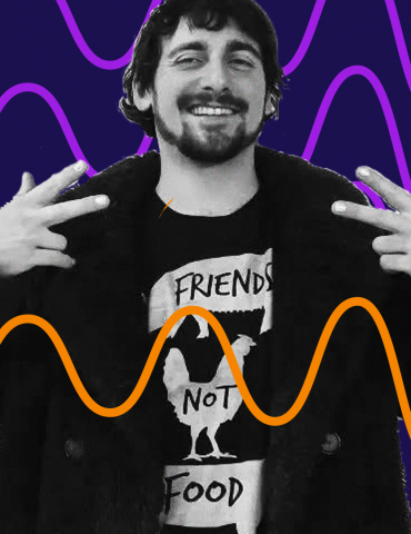 DJ Keano smiles and makes peace signs to the sides of his shoulders