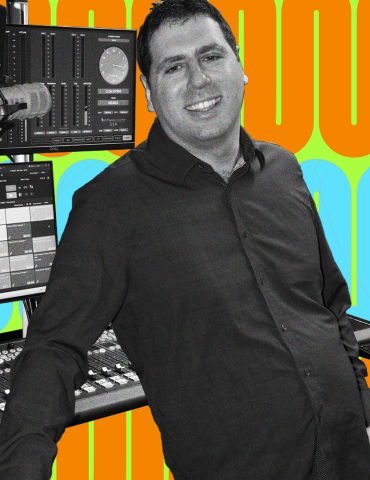 Matt leans back while smiling at the camera, recording equipment behind him